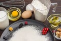 Ingredients for baking berry pie. Berries, flour in black plate. Measuring cup with flour, glass of milk, broken egg Royalty Free Stock Photo