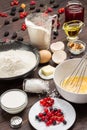 Ingredients for baking berry pie. Berries, flour in black plate. Measuring cup with flour, glass of milk, broken egg. Metal whisk Royalty Free Stock Photo