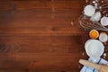 Ingredients for baking dough including flour, eggs, milk, whisk and rolling pin on wooden rustic background