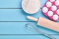 Ingredients for baking, eggs, flour, whisk and rolling pin on blue background Royalty Free Stock Photo