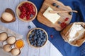 Ingredients for baking lie on a light wooden background with a blue kitchen towel. butter, berries and wooden Royalty Free Stock Photo