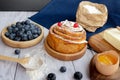 Ingredients for baking lie on a light wooden background with a blue kitchen towel. flour, eggs, butter, berries and wooden Royalty Free Stock Photo