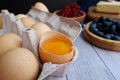 ingredients for baking lie on a light wooden background with a blue kitchen towel. flour, eggs, butter, berries, a bun and wooden Royalty Free Stock Photo