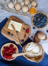 Ingredients for baking lie on a light wooden background with a blue kitchen towel. flour, eggs, butter, berries and wooden Royalty Free Stock Photo