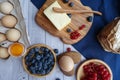 Ingredients for baking lie on a light wooden background with a blue kitchen towel. flour, eggs, butter, berries and wooden Royalty Free Stock Photo