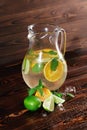 Ingredients for a citrus lemonade on a wooden background. Lime, oranges, mint next to a jar of fruit juice. Cafe drinks. Royalty Free Stock Photo