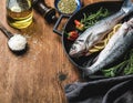 Ingredients for cookig healthy fish dinner. Raw uncooked seabass with rice, olive oil, lemon slices, herbs and spices Royalty Free Stock Photo
