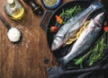 Ingredients for cookig healthy fish dinner. Raw uncooked seabass with rice, olive oil, lemon slices, herbs and spices