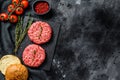 Ingredients for cooking burgers. Minced beef patties, buns, tomatoes, herbs and spices. Black background. Top view. Copy Royalty Free Stock Photo