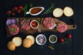 Ingredients for cooking burgers. Raw ground beef meat cutlets on wooden chopping board, red onion, cherry tomatoes Royalty Free Stock Photo