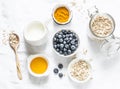 Ingredients for cooking coconut milk turmeric blueberry oatmeal porridge on a light background, top view. Gluten free, vegetarian