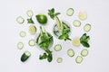 Ingredients for cooking cold spring drink with cucumber, pieces of lime, fresh leaves mint and ice cubes on soft white background. Royalty Free Stock Photo