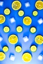 Ingredients for cooking cold spring lemonade drink with cucumber, pieces of lemon, ice cubes on blue background, top view Royalty Free Stock Photo