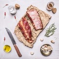 Ingredients for cooking double raw lamb ribs on paper with a knife, garlic, salt, butter and herbs on white wooden rustic backgro