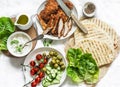 Ingredients for cooking greek gyros - chicken schnitzel, lettuce, grilled tortillas, greek yogurt tzatziki sauce, tomatoes, olives