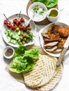 Ingredients for cooking greek gyros - chicken schnitzel, lettuce, grilled tortillas, greek yogurt tzatziki sauce, tomatoes, olives