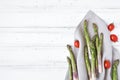 Ingredients for cooking healthy breakfast: fresh asparagus, tomatoes on white table. Rustic style composition. Flat lay, top view Royalty Free Stock Photo