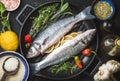Ingredients for cooking healthy fish dinner. Raw uncooked seabass with rice, lemon, herbs and spices on black grilling Royalty Free Stock Photo