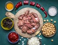 Ingredients for cooking lamb canned chickpeas condiment hot red pepper tomato paste prunes sliced onions on a cutting board on woo