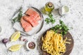 Ingredients for cooking lunch - raw salmon, dry pasta tagliatelle, cream, olive oil, spices and herbs. On a light background Royalty Free Stock Photo