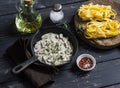 Ingredients for cooking pasta with creamy mushroom sauce - dry pasta, mushroom cream sauce, olive oil and spices. On a dark wooden Royalty Free Stock Photo