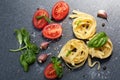Ingredients for cooking pasta. Italian tagliatelle pasta with tomato on black wooden background. Royalty Free Stock Photo