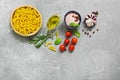 Ingredients for cooking pasta with tomato sauce. Fusilli, tomatoes, basil, olive oil, pink salt, pepper, rosemary and garlic on a Royalty Free Stock Photo