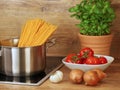 ingredients for cooking pasta with tomato sauce at home, saucepan with raw pasta on stove Royalty Free Stock Photo