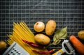 Ingredients for cooking: potatoes, salt, pepper, onion, garlic on a dark stone table. Metal grid. Royalty Free Stock Photo