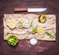 Ingredients for cooking raw cod on peper knife lemon arugula lettuce salt oil rustic wooden background top view close up