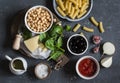 Ingredients for cooking rigatoni pasta with chickpeas, spinach and olives in a tomato sauce on a dark background, top view. Royalty Free Stock Photo