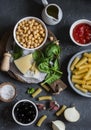 Ingredients for cooking rigatoni pasta with chickpeas, spinach and olives in a tomato sauce on a dark background, top view. Royalty Free Stock Photo