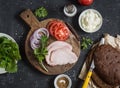 Ingredients for cooking sandwich - roasted pork, tomato, red onion, arugula, rye bread, soft cheese. Royalty Free Stock Photo