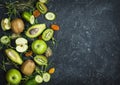 Ingredients for cooking smoothie. Organic green vegetables and fruits on black stone background. Copy space, top view