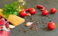 Ingredients for cooking spaghetti - raw spaghetti, cherry tomatoes, chili peppers, garlic, herbs, spices and olive oil on a black Royalty Free Stock Photo