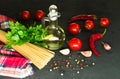 Ingredients for cooking spaghetti - raw spaghetti, cherry tomatoes, chili peppers, garlic, herbs, spices and olive oil on a black Royalty Free Stock Photo