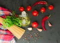 Ingredients for cooking spaghetti - raw spaghetti, cherry tomatoes, chili peppers, garlic, herbs, spices and olive oil on a black Royalty Free Stock Photo