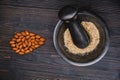 Ingredients for cooking, top view. Preparation of almond flour. Grind nuts in a mortar on a wooden dark background