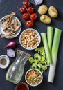 Ingredients for detox soup - bouillon in bottle, celery, chickpeas, leeks, tomatoes, red onions, spices on dark background, top vi Royalty Free Stock Photo