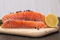 Ingredients. Fresh salmon steak surrounded by lemon and spices on a wooden board. Black and white background. Royalty Free Stock Photo