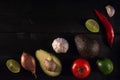 Ingredients for guacamole, avocado, lime, onion, garlic, tomato, pepper on dark wooden background, free space, top view Royalty Free Stock Photo