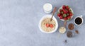 Ingredients for healthy breakfast concept banner. Bowl of oatmeal porridge, strawberries, milk and seeds on stone background with