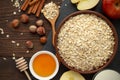 Ingredients for healthy breakfast: rolled oat flakes, milk, honey, hazelnut, cinnamon on dark rustic wooden table. Royalty Free Stock Photo