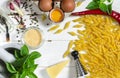 Penne Pasta, green basil, parmesan, sesame, garlic, chilli, eggs lie on a white tree table