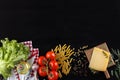 Ingredients for Italian dish. Parmesan cheese, pasta and fresh vegetables. On an old black wooden background. Royalty Free Stock Photo