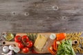 Ingredients for Italian dish. Parmesan cheese, pasta and fresh vegetables. On an old wooden background. Royalty Free Stock Photo