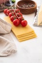 Ingredients for Italian lasagna with fresh cherry tomatoes and green basil leaves on sheets of dried pasta. Copy space. Royalty Free Stock Photo