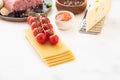Ingredients for Italian lasagna with fresh cherry tomatoes and green basil leaves on sheets of dried pasta. Copy space. Royalty Free Stock Photo