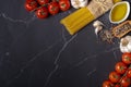 Ingredients for italian pasta. Spaghetti, tomatoes, olive oil, garlic and rosemary on dark gray marble kitchen table Royalty Free Stock Photo