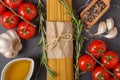 Ingredients for italian pasta. Spaghetti, tomatoes, olive oil, garlic and rosemary on dark gray marble kitchen table Royalty Free Stock Photo